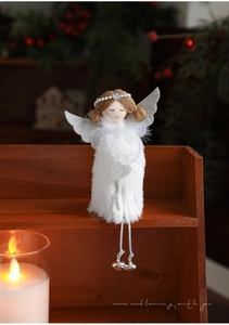 Detail of plush angel doll with silver wings and heart bell on a festive wooden shelf