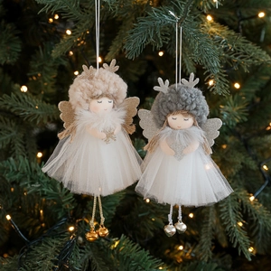 Plush Christmas angel dolls with antlers and bells hanging on a glowing festive Xmas tree