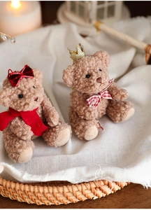 Close-up of cute plush teddy bears with crown and bow on warm fabric background