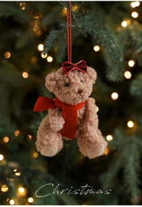 Detail of a brown curly teddy bear plush with red bow and scarf for Christmas decor