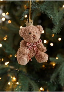 Detail of cute light brown teddy bear ornament with gold crown on a festive Christmas tree