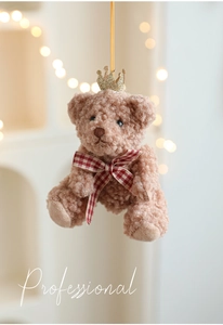 Close-up of a brown plush teddy bear with a gold crown and checkered bow tie charm