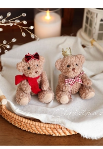 Detail view of two plush teddy bears with red scarves and a crown for Christmas decor