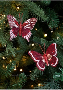Dettaglio di fermagli a farfalla glitter rossi con stelle d'oro su albero di Natale