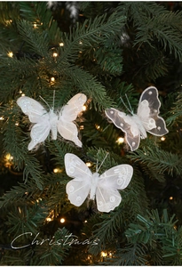 Dettaglio di farfalle decorative bianche con glitter e perle su rami di albero di Natale
