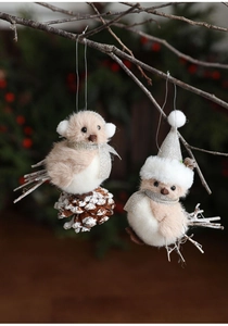 Close-up of plush bird ornaments with snow-dusted pine cones and festive hats