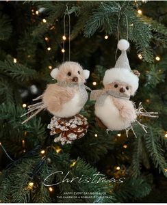 Close-up of grey plush bird ornaments with pine cones and hats on a Christmas tree