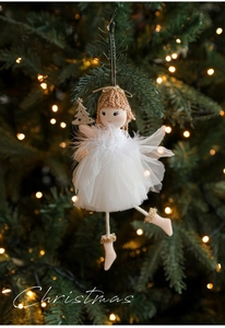 Detail of plush angel ornament with mesh dress and gold tree hanging on Christmas tree