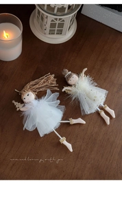Detail of plush angel ornaments with mesh skirts and wooden heads on a wooden surface