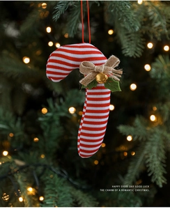 Detail of red and white candy cane ornament with a burlap bow and bell on Christmas tree