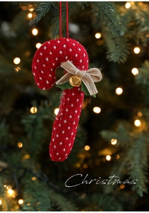Detail of red knitted candy cane ornament with burlap bow and bell on Christmas tree