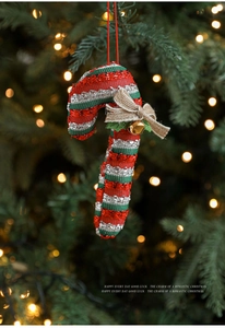 Detail of sequined candy cane ornament with burlap bow and gold bell on Xmas tree