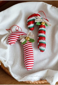 Detailed view of striped fabric candy cane ornaments with linen bows and gold bells