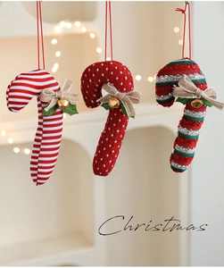 Detailed view of red and white fabric candy cane ornaments with bells and jute bows