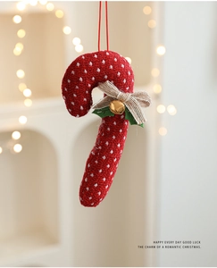 Detail of red polka dot candy cane ornament with a jute bow and small gold bell