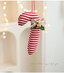 Detail of red and white knitted candy cane with burlap bow and gold bell ornament