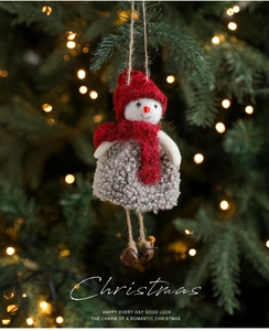 Detail of plush Christmas snowman ornament with red knit hat and bells on tree