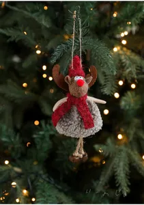 Plush Christmas reindeer ornament with red hat and bells hanging on a lit Xmas tree