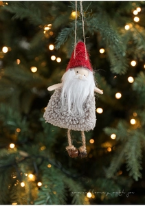 Detail of plush Christmas gnome ornament with red felt hat and bells on Xmas tree