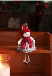 Detail of plush snowman ornament with red knit hat and bell accents on a wooden stair
