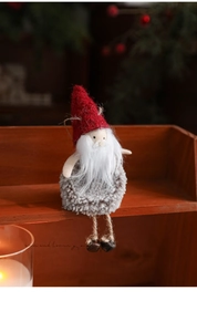 Detail of plush Christmas gnome with red felt hat, grey yarn body, and hanging metal bells