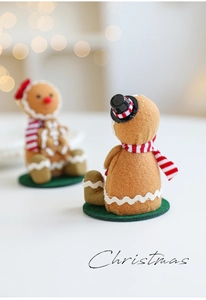 Close-up of plush gingerbread man with red striped scarf and warm bokeh Christmas lighting