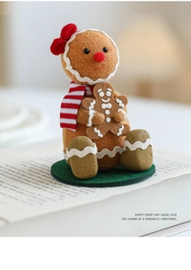Detail of Christmas gingerbread man felt ornament with red bow and scarf on white book