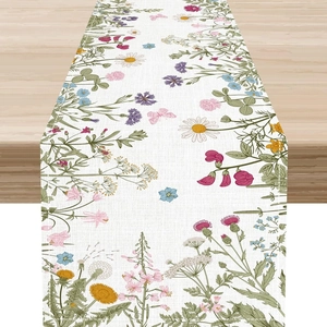 Camino de mesa de lino con flores de primavera y mariposas sobre mesa de madera clara
