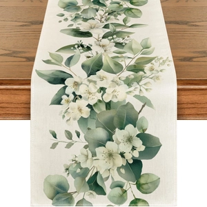 Detalle del camino de mesa de lino con flores de acuarela sobre mesa de madera oscura