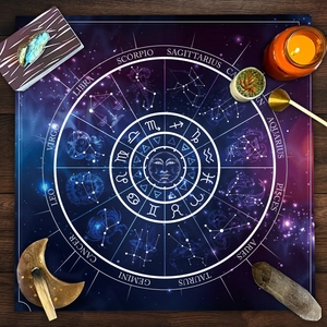 Macro shot of tarot cloth featuring zodiac signs, sun patterns, and nebula background