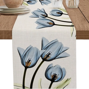Detalle de camino de mesa de lino con tulipanes azules sobre mesa de comedor de madera