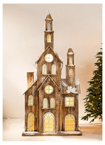 Détail d'une grande maison de Noël vintage éclairée en bois avec effets de neige