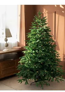 Close-up of a green luxury Christmas tree with warm LED lights and a metal base