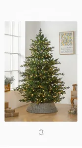 Detail of lush green artificial Christmas tree with warm glowing lights and rattan base