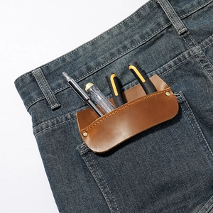 Brown leather pocket tool organizer with metal rivets shown in a blue jeans pocket