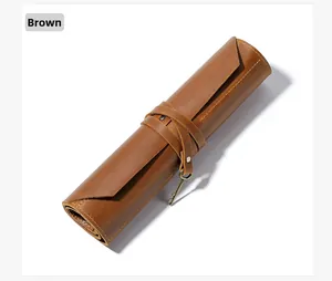 Detail of a brown leather roll-up pencil case with a vintage key charm and leather strap