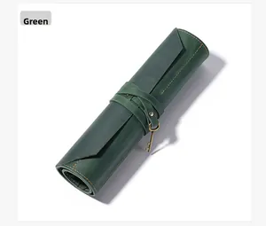 Detail of dark green vintage leather roll pencil case with bronze key charm and yellow stitching