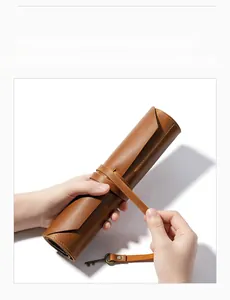 Detail of genuine brown leather roll-up tool pouch with cord wrap and vintage key charm