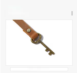 Detail of leather tool organizer strap with antique bronze hardware and key pendant