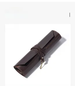 Macro detail of brown leather roll-up tool bag with vintage metal key pendant and stitching