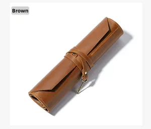 Close-up of brown leather tool roll pouch featuring a vintage key pendant and tie strap