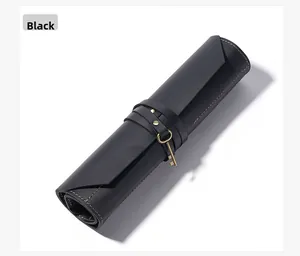 Detail of black leather roll-up tool bag with yellow stitching and vintage key charm