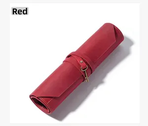 Detailed view of red leather roll pouch with bronze key charm and vintage strap closure