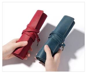 Dettaglio dell'astuccio in pelle con cuciture a contrasto e ciondolo chiave vintage