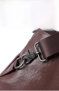 Détail macro du fermoir en métal gris et du cuir grainé sur un sac bandoulière marron