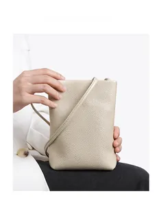 Detail shot of beige pebble grain leather crossbody phone bag with matching shoulder strap