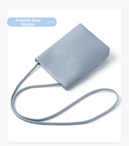 Close-up of litchi texture on blue genuine leather phone bag with slim shoulder strap