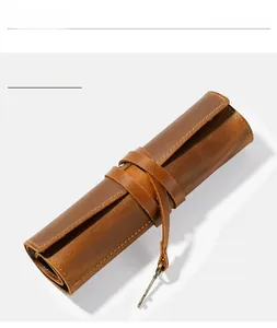 Macro shot of brown crazy horse leather pen roll with vintage key charm and strap detail