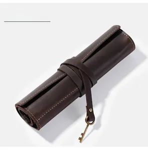 Detail of vintage coffee leather roll pencil case with decorative key charm and yellow stitching