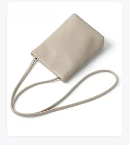 Top-down macro view of beige pebble grain leather crossbody phone bag with fine strap